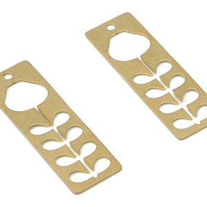 Puede incluir: Dos pendientes de metal de color dorado con un diseño de flor. Cada pendiente presenta una flor con un tallo y hojas.