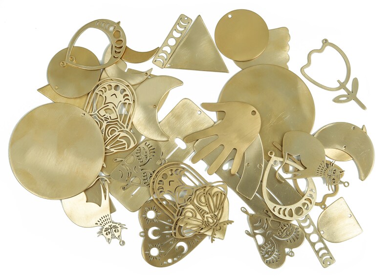 May include: A collection of brass metal shapes, including circles, hearts, moons, butterflies, and a hand. The shapes have intricate cutouts and designs.