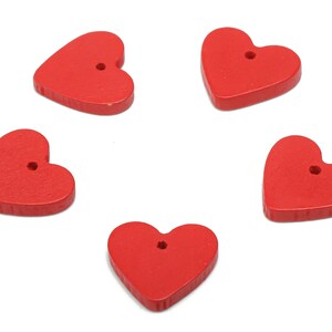 May include: Five red wooden heart-shaped buttons with a hole in the centre. The buttons are arranged in a circle on a white background.