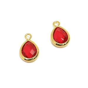 May include: Two gold-tone teardrop-shaped charms with red crystal accents.
