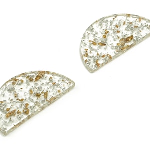 Może przedstawiać: Dwa przezroczyste, półokrągłe podkładki z żywicy z złotymi i srebrnymi drobinkami.