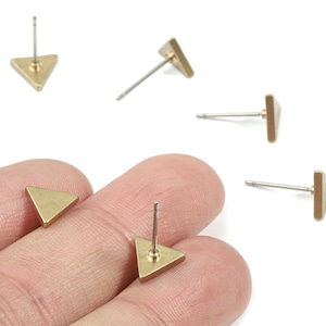 Peut inclure: Une collection de petites boucles d'oreilles clous triangulaires de couleur or. Les boucles d'oreilles ont un design géométrique simple avec une tige pour l'insertion. Les boucles d'oreilles sont présentées sur fond blanc.