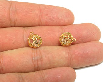 May include: Two small, gold-colored, openwork sphere charms with a small loop at the top for attaching to jewelry. Each charm has a clear, faceted stone inside. The charms are shown against a light background.