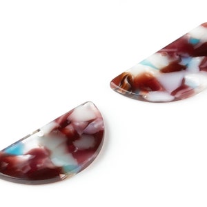 May include: Two half-circle shaped resin hair clips with a marbled pattern in shades of brown, white, and blue.