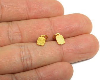 May include: Two small, gold-colored charms. One charm is rectangular with a loop at the top, and the other is a square shape with a loop and Chinese characters. The charms are displayed on a person's hand.