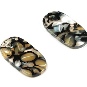 May include: Two oval-shaped, black, white and brown patterned hair clips.