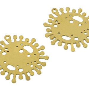 Puede incluir: Dos abalorios de metal de color dorado en forma de sol con una superficie texturizada y un agujero en la parte superior para colgar.