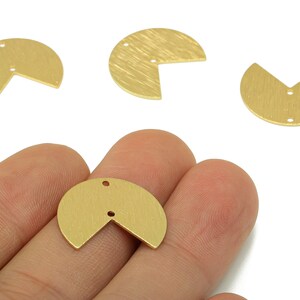 May include: Close-up of several gold-coloured, semi-circular metal jewellery components. Each piece has a textured surface and a small, cut-out corner. Some pieces have two small holes for attaching to other components. The components are on a white background.