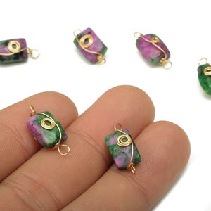 May include: Ruby zoisite gemstone beads with gold wire wrapping. The beads are a mix of green and pink, with a polished, irregular shape. The gold wire is wrapped around the bead and forms a loop for stringing.