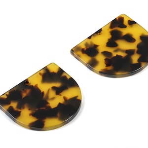 Puede incluir: Dos piezas de resina con forma de semicírculo con un patrón de caparazón de tortuga y un agujero en la parte superior.