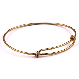 May include: A gold-toned expandable bangle bracelet with a simple, elegant design.