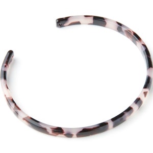 Può includere: Un cerchietto per capelli in plastica con motivo tartaruga.