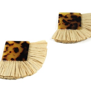 May include: A pair of earrings featuring a square resin piece with a tortoiseshell pattern and a fringe of natural raffia fibres.