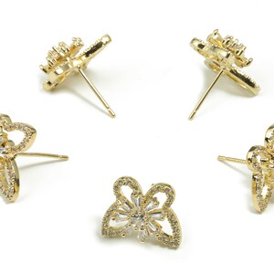 May include: A pair of gold butterfly-shaped earrings with clear cubic zirconia stones.