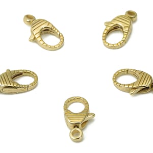 Puede incluir: Cinco cierres de langosta de metal dorado con un diseño texturizado. Los cierres son de forma ovalada y tienen un mecanismo de resorte.