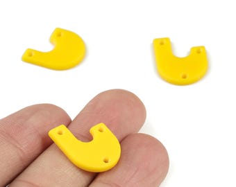 May include: Three bright yellow, U-shaped acrylic charms with small holes for stringing. One charm is held between fingers, while two others are scattered on a white surface. These charms are suitable for jewelry making or craft projects.