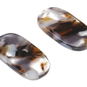 May include: Two oval-shaped agate pendants with a white, brown, and grey marbled pattern. The pendants have a hole at the top for stringing.
