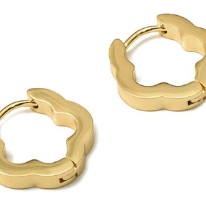 May include: A pair of gold-toned hoop earrings with a flower-shaped design. The earrings are made of metal and have a hinged closure.