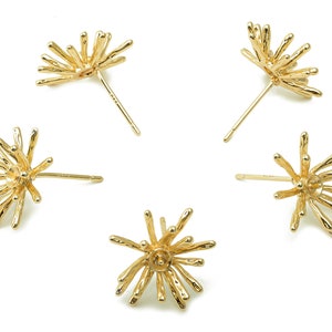 May include: Four gold-toned earrings with a starburst design. Each earring features a cluster of thin, pointed spikes radiating from a central point.