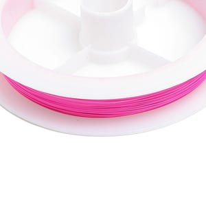 Könnte beinhalten: Eine Spule mit pinkfarbenem Garn, das um eine weiße Plastikspule gewickelt ist.