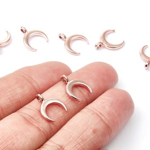 K&ouml;nnte beinhalten: Ein Set mit sechs ros&eacute;goldenen Halbmond-Anh&auml;ngern. Die Anh&auml;nger sind aus Metall und haben eine glatte, polierte Oberfl&auml;che.