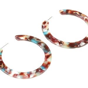 May include: A pair of large hoop earrings with a brown, white, and blue marbled pattern.