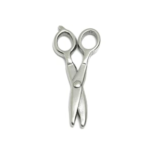 Può includere: Un ciondolo a forma di forbici color argento. Le forbici sono aperte e incrociate, con le lame rivolte verso il basso.