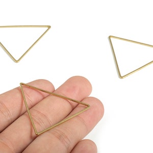 May include: Three gold triangle shaped metal hoops. The hoops are approximately 5 cm in diameter.