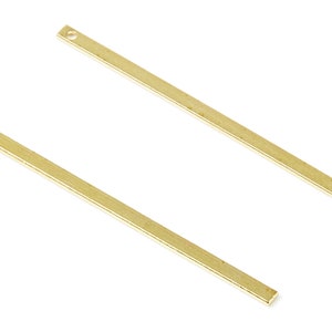 May include: Two gold-coloured metal bars with a hole at one end. The bars are straight and have a smooth, polished finish.