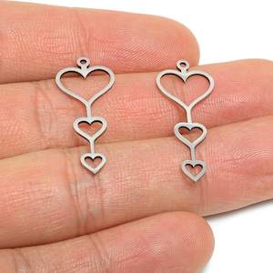 May include: Two silver-colored heart-shaped charms. Each charm features a large heart at the top, connected to two smaller hearts below. The charms have a small loop at the top for attaching to jewelry.