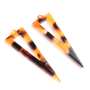 May include: Two brown and black triangle-shaped earrings with a hollow center.