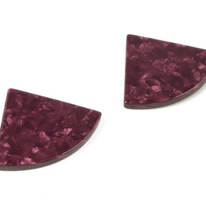 May include: A pair of maroon semi-circle earrings with a marbled pattern.