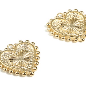 May include: Two gold heart-shaped charms with a beaded border. The hearts have a raised, sunburst-like design in the centre.