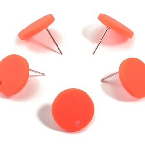 Puede incluir: Un conjunto de cinco pendientes de botón redondos de color naranja brillante. Cada pendiente tiene un pequeño agujero y un poste plateado. Los pendientes están sobre un fondo blanco.