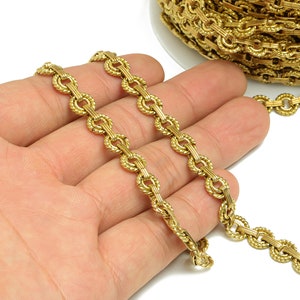 May include: Gold chain trim with a rope-like design and oval links. The chain is shown in a hand.
