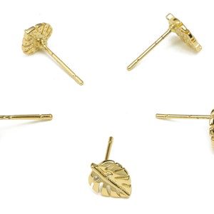 May include: Four pairs of gold-tone earrings with a leaf design. One pair features a small clear stone in the center of the leaf.