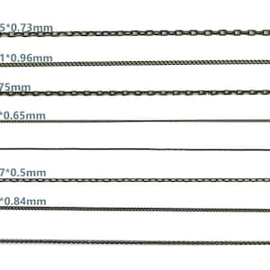 May include: A close-up of eight different chain link sizes, ranging from 0.65 mm to 4.25 mm in width. The chains are all made of metal and have a gold and black finish.