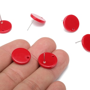 May include: Bright red, round stud earrings with a glossy finish. The earrings have a post and a small hole for attachment. Several earrings are scattered on a white background.