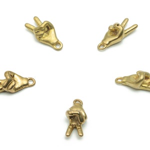 Może przedstawiać: Pięć złotych charmów w kształcie znaku pokoju z pętelką do przymocowania do biżuterii lub innych ozdób.