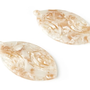 May include: Two white and brown oval-shaped resin hair clips with a swirl pattern.