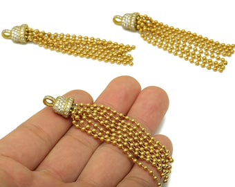 Könnte beinhalten: Goldfarbene Quastenanhänger mit einem Perlenketten-Design. Jeder Anhänger hat eine dekorative Kappe, die mit kleinen, klaren Kristallen besetzt ist. Die Quasten werden in einer Nahaufnahme gezeigt, die die Details hervorhebt.