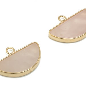 Può includere: Due ciondoli dorati a forma di mezza luna con intarsio in quarzo rosa. Ogni ciondolo ha un piccolo anello nella parte superiore per attaccarlo a una catena o un cordino.