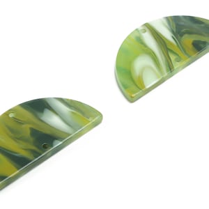 Może przedstawiać: Dwa półokrągłe elementy z żywicy w kolorze zielonym i białym z otworami do nawlekania. Elementy idealnie nadają się do tworzenia biżuterii lub rękodzieła.