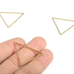 May include: Three gold triangle shaped metal frames. The frames are open and appear to be for jewellery making.