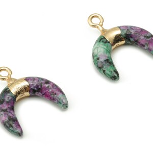 May include: Two gold crescent moon charms with a green and purple stone design.