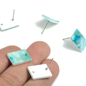 Puede incluir: Pendientes cuadrados con diseño veteado turquesa y blanco. Los pendientes tienen cierre de poste. Los pendientes tienen forma geométrica y son un accesorio de moda.