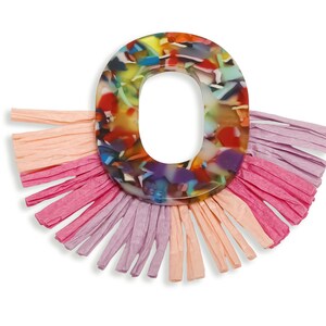May include: A colourful, abstract letter "O" pendant with a clear centre, surrounded by a fringe of pink, peach, and lavender paper. The pendant has a marbled, multi-coloured design.