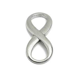 Könnte beinhalten: Ein silberner Anhänger in Form eines Unendlichkeitszeichens. Der Anhänger ist aus Metall und hat eine glatte, polierte Oberfläche.