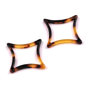 May include: Two tortoiseshell hair clips in the shape of a star. The clips are made of plastic and have a brown and yellow mottled pattern.