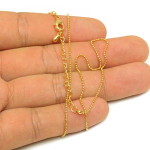 Puede incluir: Un collar de cadena de oro con cierre de langosta. La cadena está hecha de pequeñas cuentas redondas.